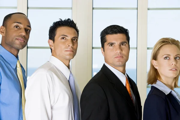 Side profile of three businessmen and a businesswoman standing in a row