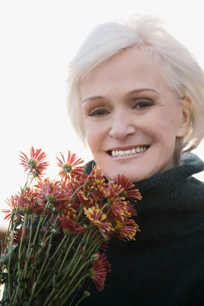 Portrait of a senior woman holding bunch of flowers and smiling