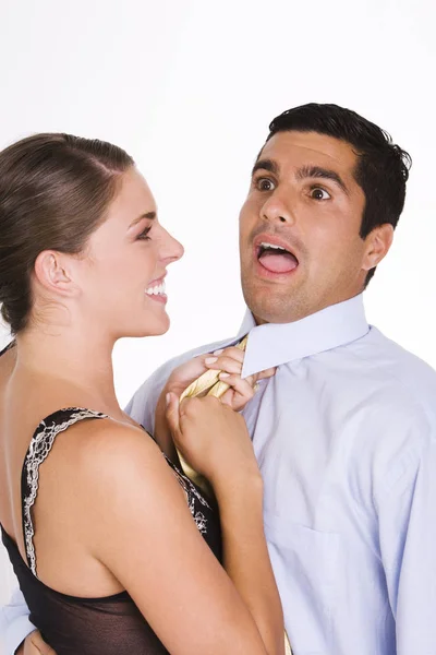 Side profile of a young woman choking a mid adult man with his tie