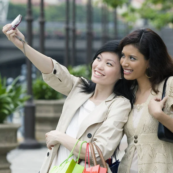 Close-up of two young women taking picture of themselves with a mobile phone