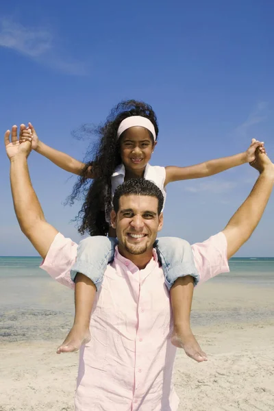 Portrait of a mid adult man carrying his daughter on his shoulders
