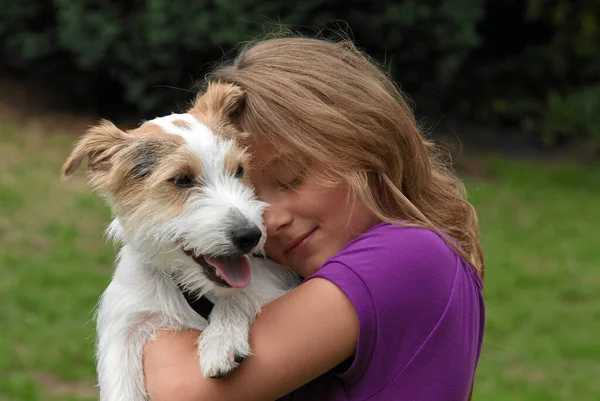 腕に犬を抱えている若い女性は — ストック写真