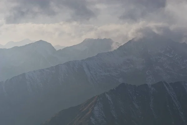 Eine Reihe Von Bergen Durch Dunkle Wolken — Stockfoto