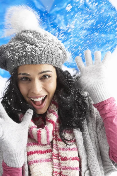 Young Woman Wearing Warm Winter Clothes And Hat Being Hit By Snowball In Studio