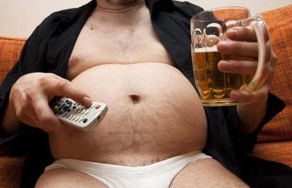 胖男人和啤酒桶坐在沙发上 — 图库照片