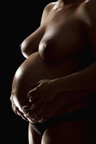 pregnant woman holding hands on black background