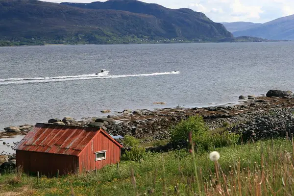 ノルウェーのフィヨルドの石の海岸にある赤い小屋です — ストック写真