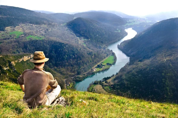 adventurer sitting and looking on a panorama of Ain river