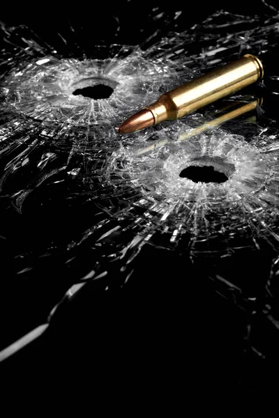 bullet holes in glass with bullet - broken glass isolated on black