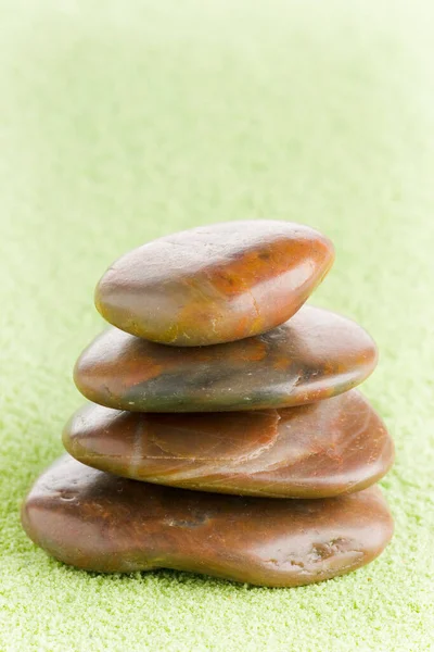 brown flat stones in balance on green sand