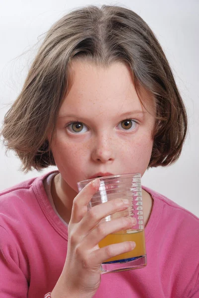 一个年轻的女孩喝桔子汁玻璃 — 图库照片