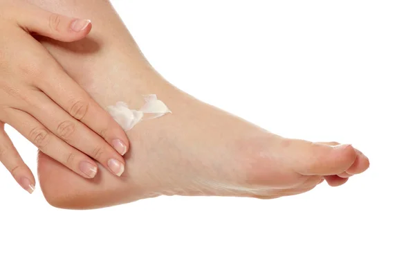 女性手を白で隔離されクリームの保湿と足の治療 — ストック写真