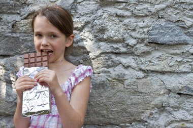 7-year girl eating a big chocolate bar clipart