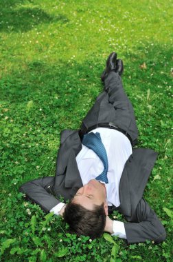 Senior people series - mature business man lying in green grass and relaxing clipart