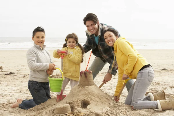 Famiglia Costruzione Sandcastle Sulla Spiaggia Invernale Foto Stock Royalty Free