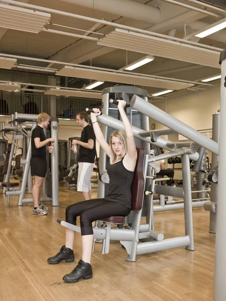 Meisje Met Een Oefening Machine Een Healthclub Met Twee Mannen — Stockfoto