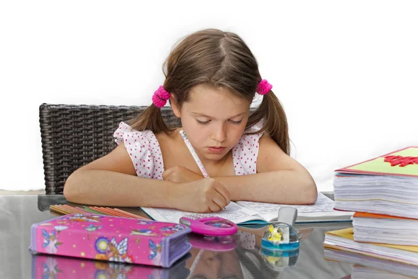 7岁的女孩坐在桌边做作业 — 图库照片