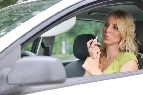 年轻的金发女人在车里用口红化妆 — 图库照片