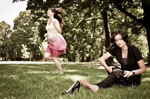 Jedna Kobieta Biegnie Boso Parku Druga Zdejmuje Buty — Zdjęcie stockowe