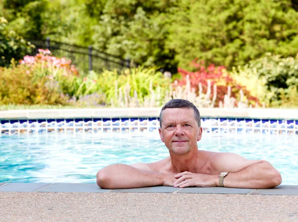 大男人在后花园的一个现代游泳池边休息 微笑着面对着摄像机 — 图库照片