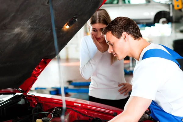 woman talks to auto mechanic in workshop