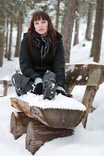 Genç Bir Kadın Karlı Ormanda Tahta Bir Bankta Oturuyor — Stok fotoğraf