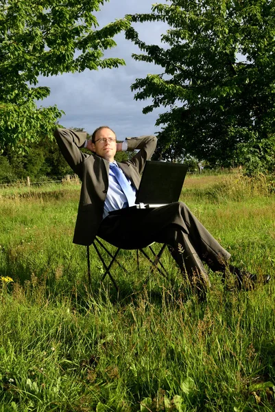ノートパソコンで草の上に座っているビジネスマンは — ストック写真