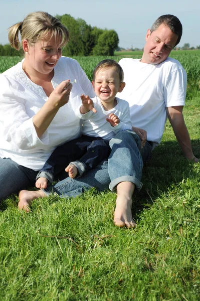 牧草地で幸せな両親と幼児は — ストック写真