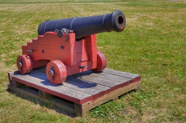 Klein Zwart Veld Kanon Een Rode Steun Zittend Een Grasveld — Stockfoto
