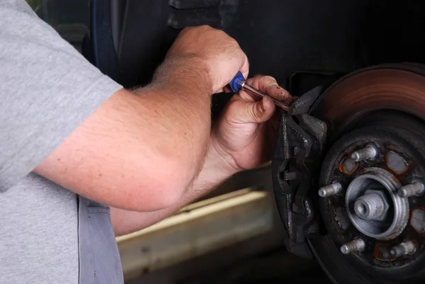 ガレージの車輪を修理する車の整備士 — ストック写真