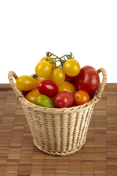 Una Canasta Muchos Tomates Orgánicos Diferentes Una Tabla Cortar Bambú — Foto de Stock