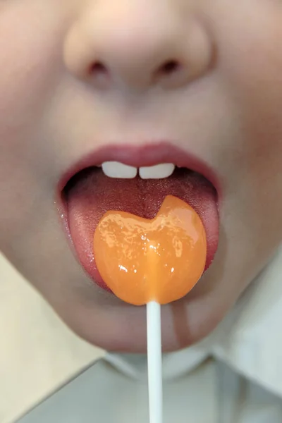 Jong Meisje Likken Een Oranje Lolly Vorm Van Een Hart — Stockfoto