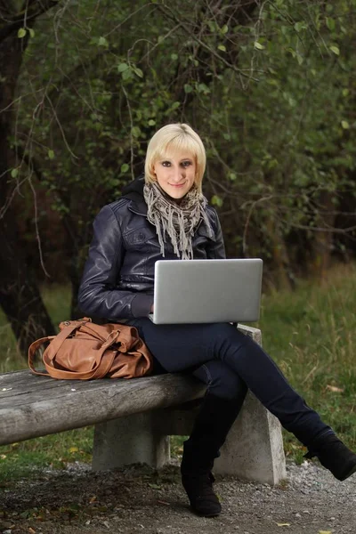 坐在室外长椅上的女用笔记本电脑 — 图库照片