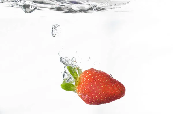 Studioaufnahme Einer Ins Wasser Fallenden Erdbeere Auf Weißem Hintergrund — Stockfoto