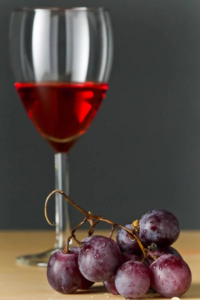 赤ワインと灰色の背景を持つワインのボトルとブドウ — ストック写真