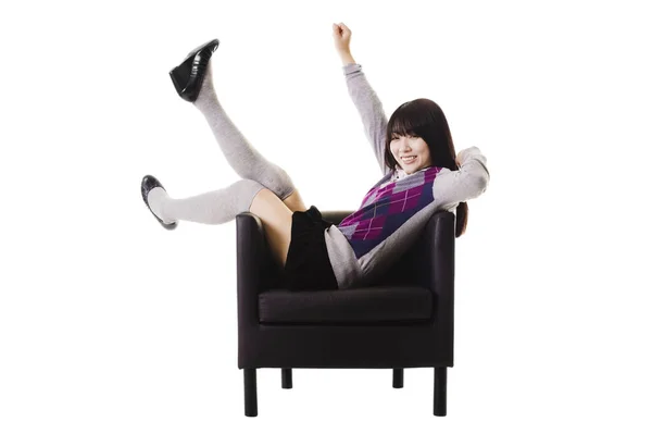 Chinese student in a school uniform sitting in a leather chair.