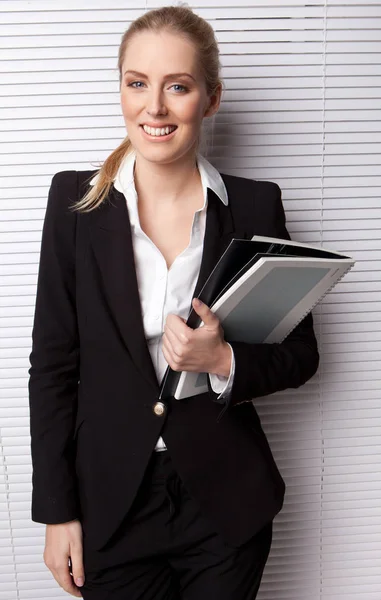 Χαμογελώντας Business Secretary Holding File Στέκεται Ενάντια Ένα Λευκό Τυφλό — Φωτογραφία Αρχείου