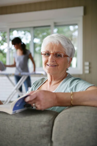 Older woman relaxing while someone else does the ironing