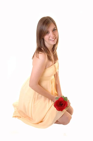 Piękna Nastolatka Żółtej Sukience Czerwoną Różą Dłoni Klęcząca Podłodze Studio — Zdjęcie stockowe
