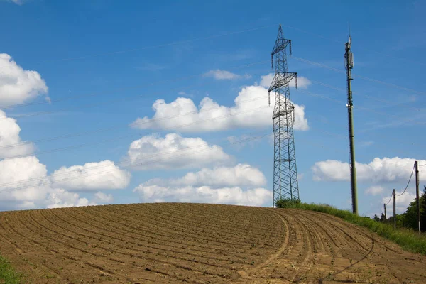 Brązowe Pole Słupami Elektrycznymi Wieżami Komórkowymi Wsi Horyzontem Błękitnym Niebem — Zdjęcie stockowe
