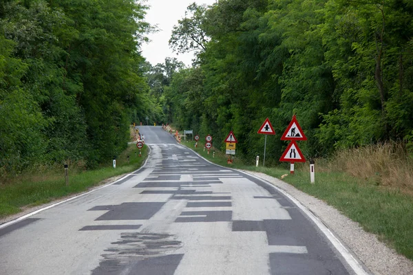 Droga Naprawionymi Nawierzchniami Asfaltowymi Znakami Placu Budowy Przez Las Pochmurnym — Zdjęcie stockowe