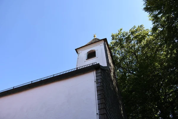 古旧的木制建筑上 有一个拱顶立着一只装饰鸟 上面挂着一个有纹理的 风吹日晒的金属屋顶 — 图库照片