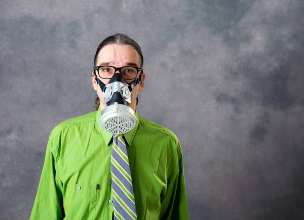 灰色の背景の前にガスマスクをした緑色のシャツを着た若いビジネスマン — ストック写真