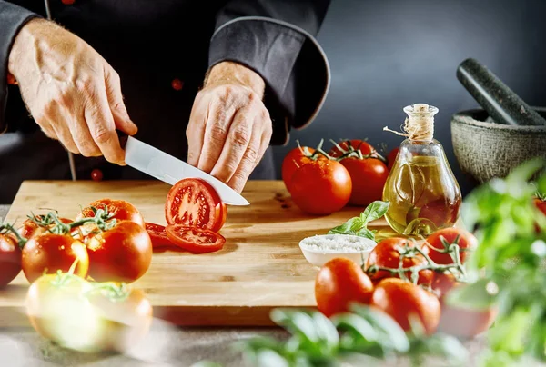 Hombre Con Traje Cocinero Cortando Tomates Maduros Finas Lonchas Sentadas — Foto de Stock