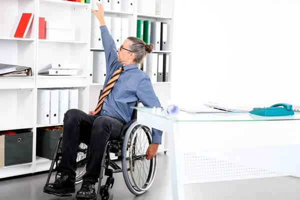 坐在轮椅上的残疾商人在办公室工作 — 图库照片
