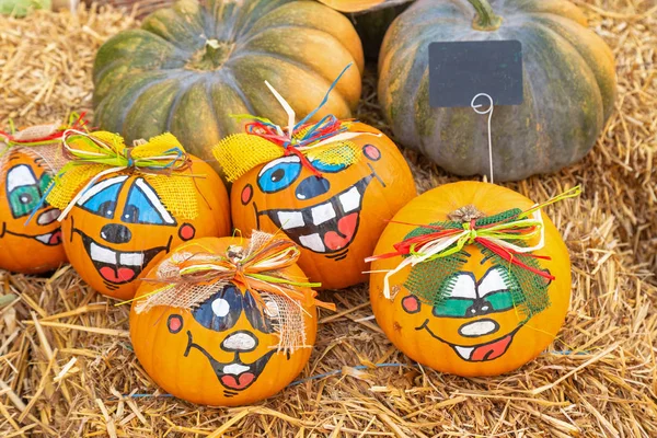 Painted pumpkins with funny faces on straw