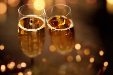 Close up champagne glasses on festive dark background with golden bokeh clipart