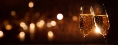 Champagne glasses on festive dark background with golden bokeh clipart