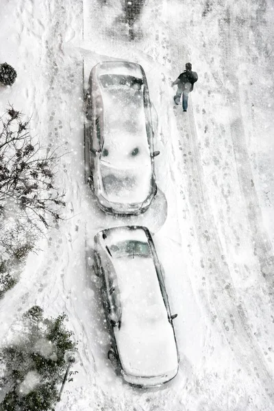 在结冰的街道上 人们开着被覆盖的停放着的汽车在雪地中行走的高程照片 — 图库照片