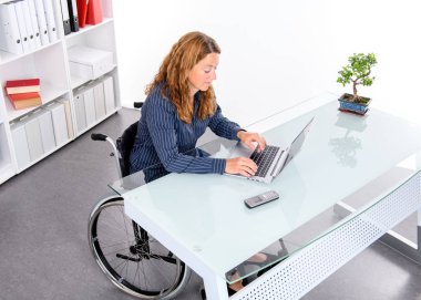 disabled businesswoman in wheelchair working  in the office clipart